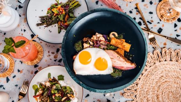 Overhead view of bowl will over easy egg and side salads