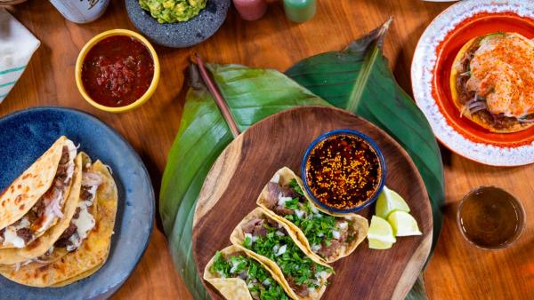 Overhead view of taco plates with sides and sauces