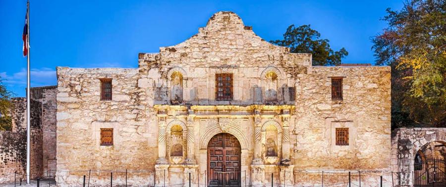 The Alamo lit up with dusk sky in background.