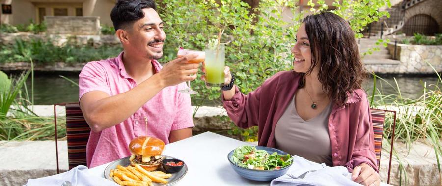 Man and woman toasting each other at the San Antonio River Walk