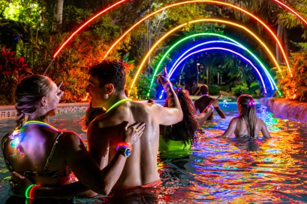 People wading under colorful lights at night.