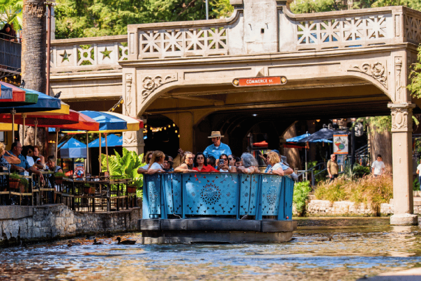 blue barge floating down the San Antonio River Walk
