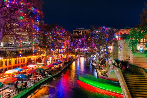 The San Antonio River Walk lit up at night with holiday lights.
