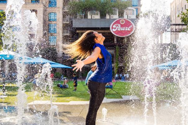 Woman enjoying the splash pads at the Pearl Lawn