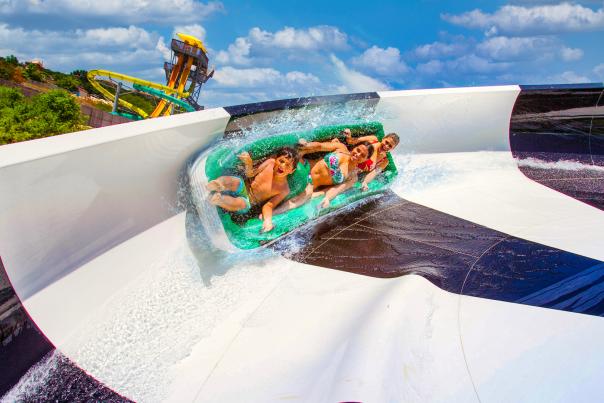 Group of three people on black and white water slide at Hurricane Harbor at Six Flags Fiesta Texas.