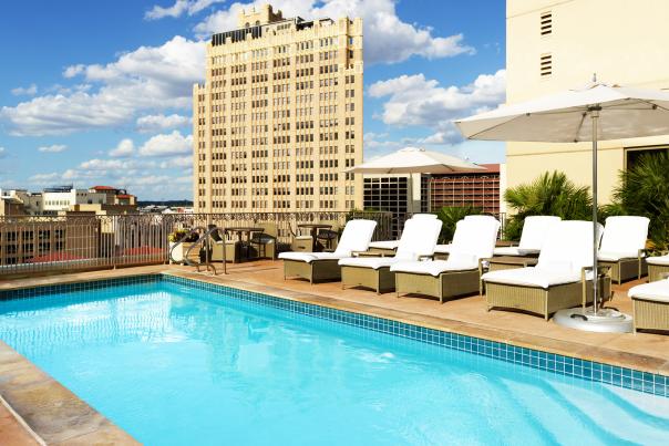 Outdoor pool at hotel with large building in distance.