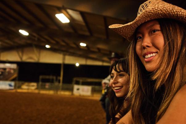 Gril in cowboy hat overlooking rodeo grounds.