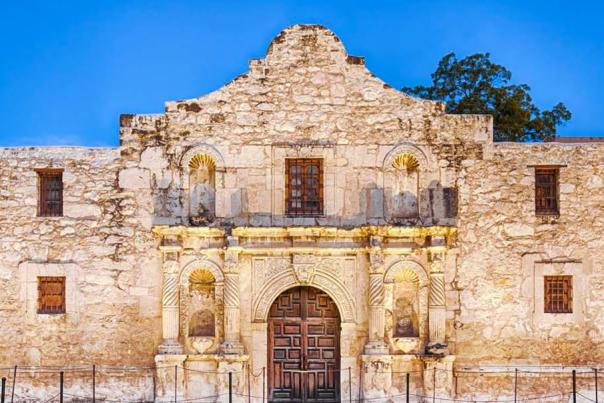The Alamo lit up with dusk sky in background.