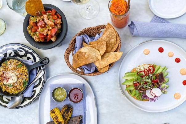Overhead view of food spread with skillet corn, chips, and plated meal