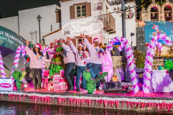 River barge at Ford Holiday River Parade with pink and white candy canes and people dressed in pink sweaters.