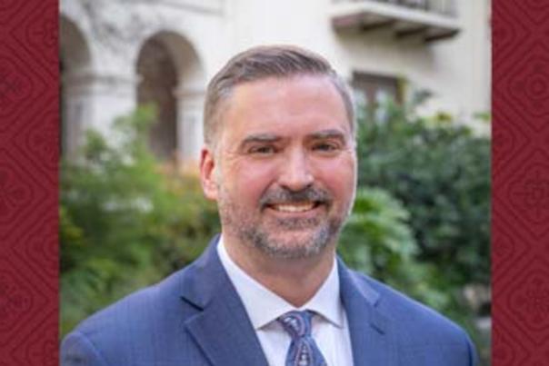 Headshot of smiling man dressed in suit and tie.
