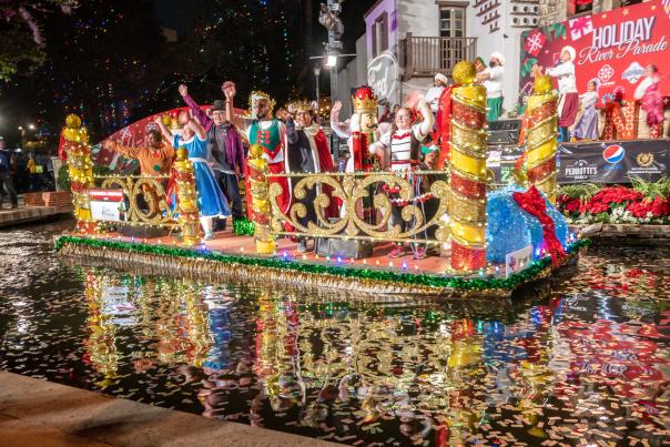 Festive decorated float with costumed patrons at Ford Holiday River Parade.