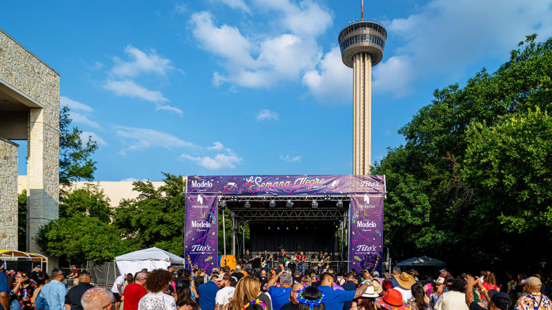 Crowd gathering in front of stage with Tower of the Americas in background.