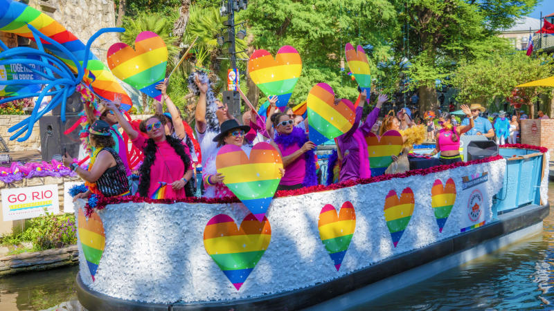 River barge with rainbow hearts and people floating on River Walk