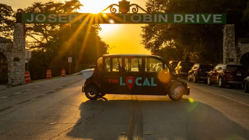 Mini car driving with sun setting on horizon in distance.