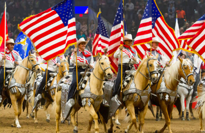 Group of riders on horses holding American flags