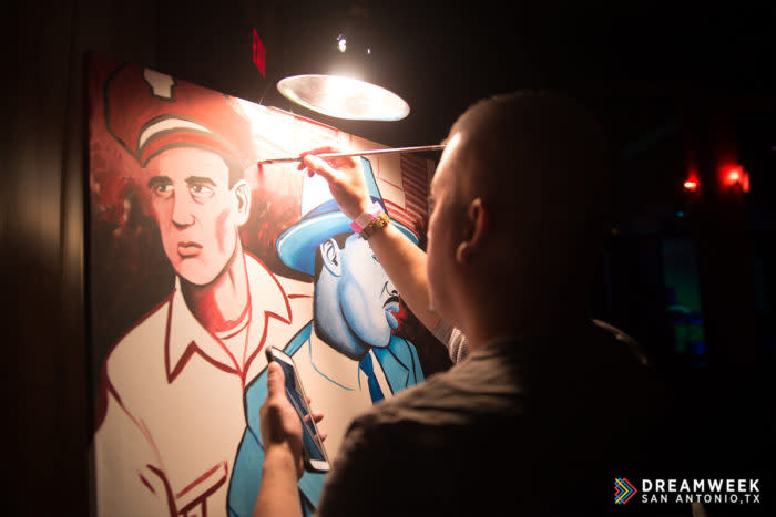 man painting in the dark with an overhead lamp