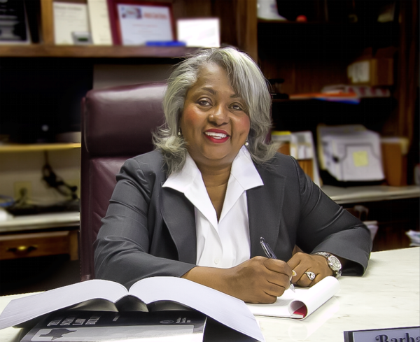 Woman in front of desk holding pen and paper