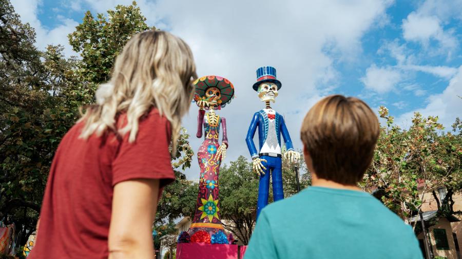 Mom and son looking at large catrina and catrino statues at Historic La Villita in San Antonio.