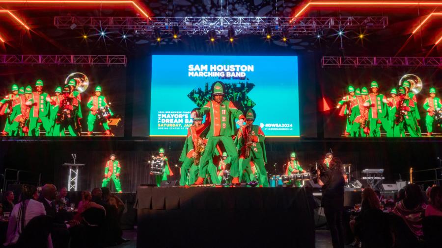 Performers in green and orange uniforms at DreamWeek San Antonio.