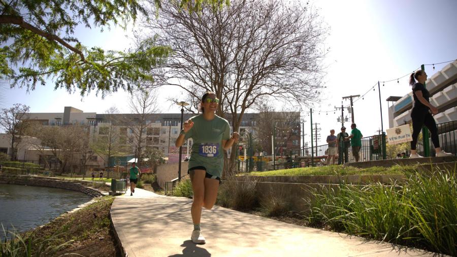 Woman running at San Antonio River Walk in Annual Emerald Run 5h.