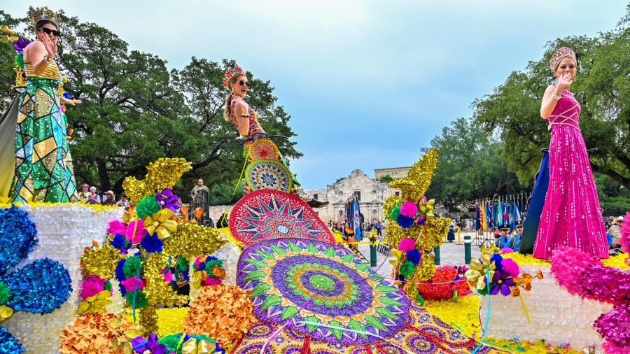 Parade participants on float dressed in elaborate dresses at Battle of Flowers parade in San Antonio in Fiesta San Antonio.