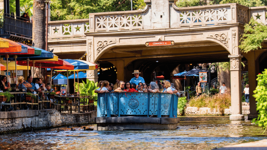 blue barge floating down the San Antonio River Walk