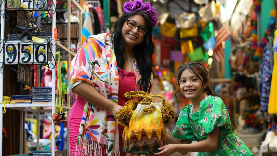 mother and daughter holding knit bag in market