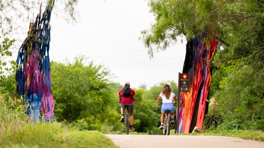 bikers riding on a trail with public art
