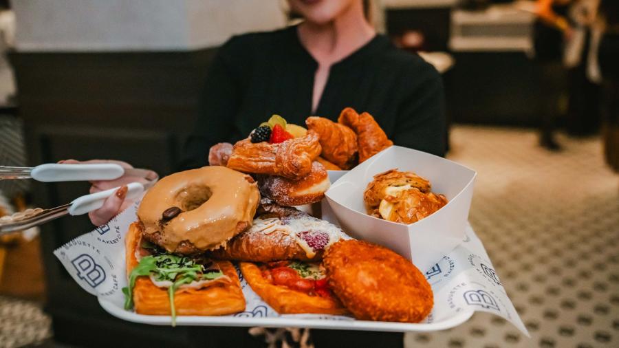 Woman holding food spread at Paris Baguette.