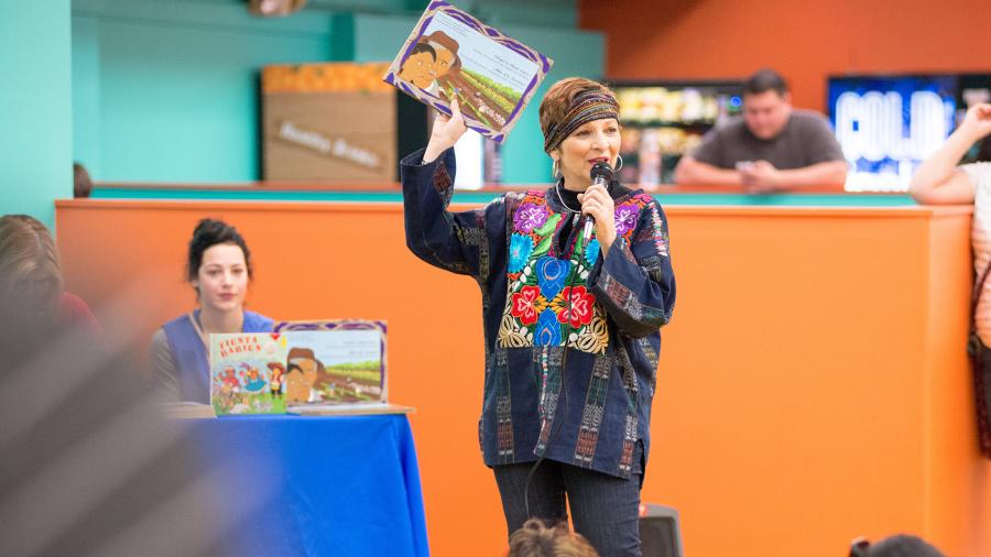 Woman holding up book at DreamWeek San Antonio event.