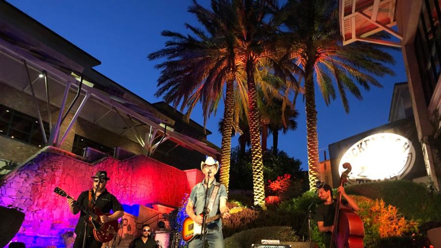 Two Tons of Steel playing in front of shopping center and palm trees.