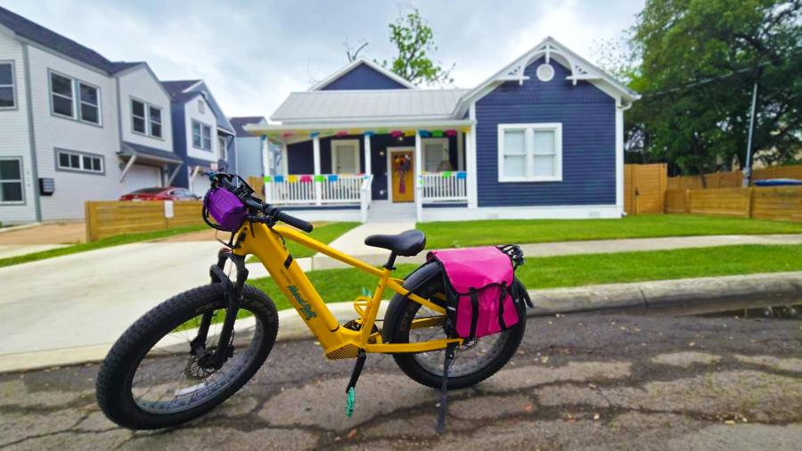 Yellow bike with carry case in front of blue house.