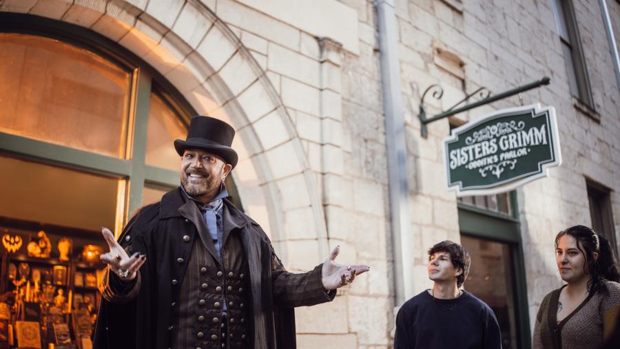 Man presenting story in front of Sisters Grimm signage.