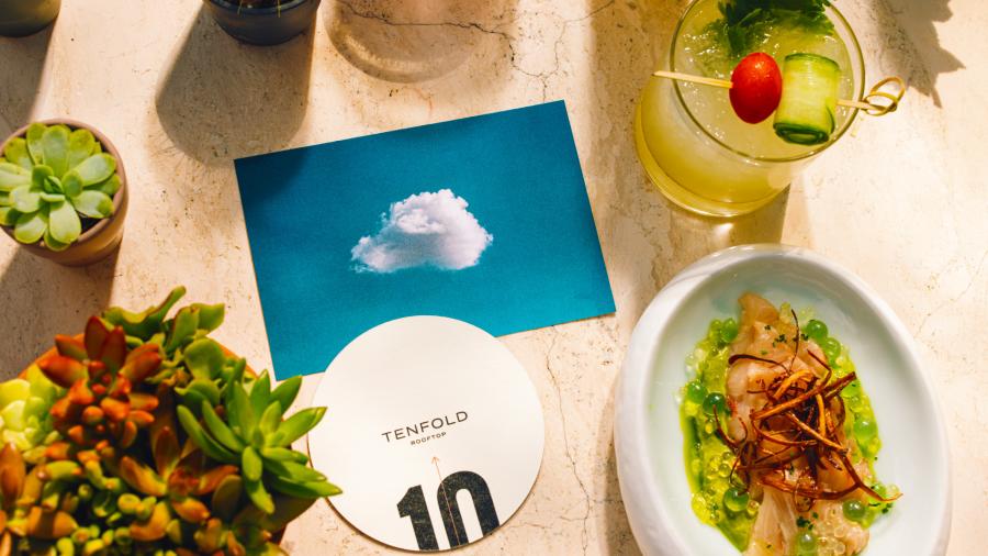 Overhead view of food and drink spread with a coaster from Tenfold Rooftop bar.