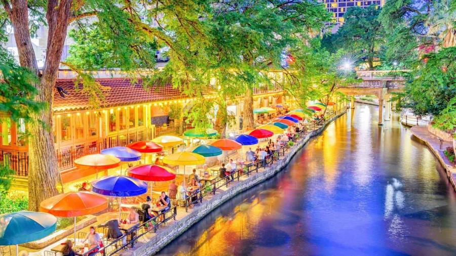 Colorful umbrellas lit up along the River Walk at dusk.