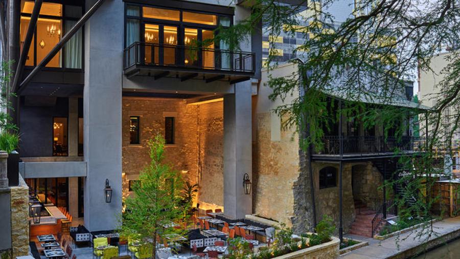 Exterior view of Canopy by Hilton - San Antonio Riverwalk hotel with patio dining on San Antonio River Walk.