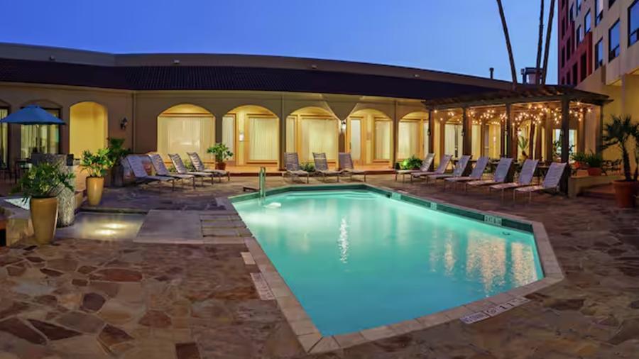 Exterior hotel pool lit up at night.