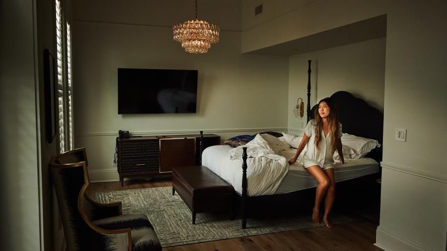 Woman getting out of bed in hotel room