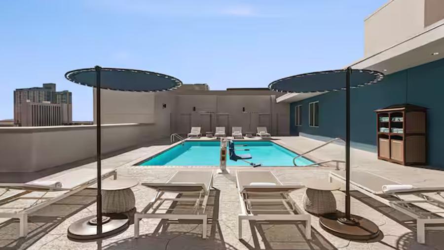 Hotel pool with shaded umbrellas on a sunny day.