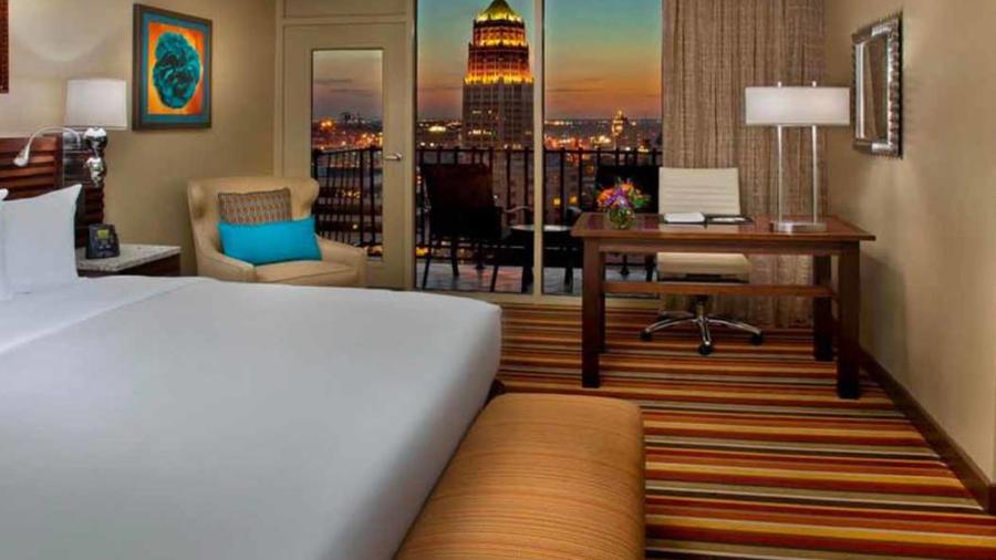Interior hotel room with colorful rug and skyline in window.