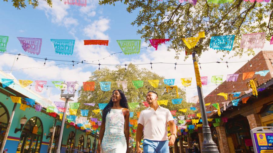 Couple walking through Historic Market Square with papel picado above them