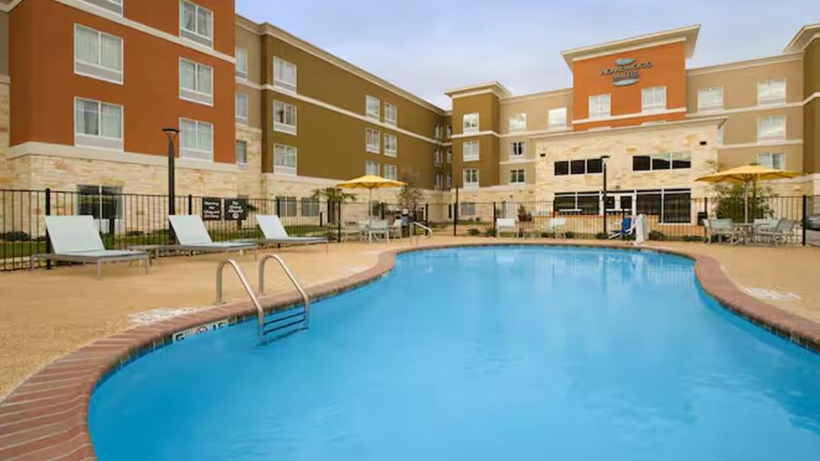 Outdoor hotel pool with hotel rooms surrounding it.
