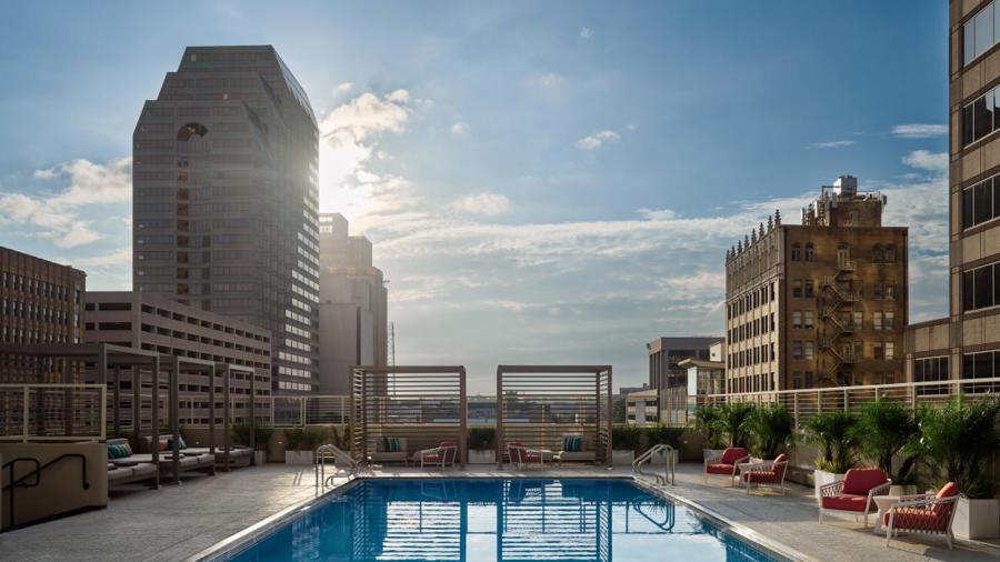 Hotel pool with sunrise and building in background.