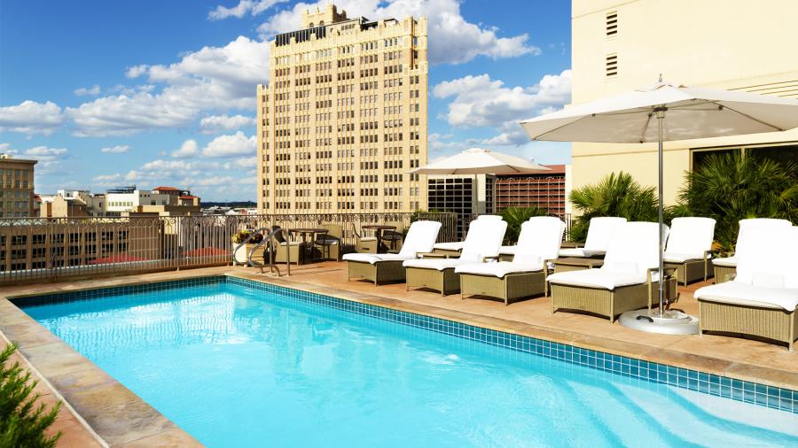 Outdoor pool at hotel with large building in distance.