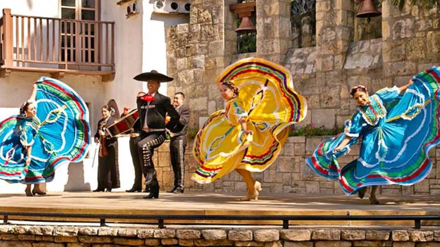 Mariachi and folklorico dancers in blue and yellow dresses.