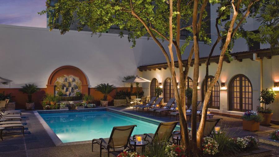 Hotel pool at dusk with pool light on.