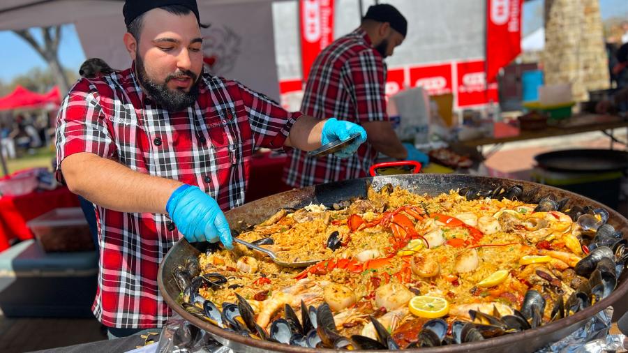 Man scooping paella onto plate.