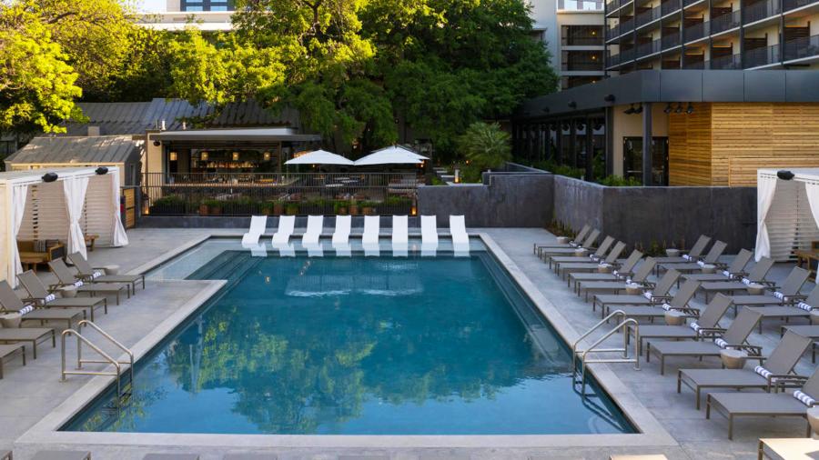 Hotel pool with lounge chairs and umbrellas at sides.