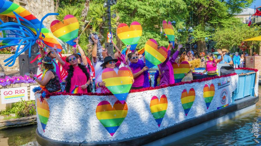 River barge with rainbow hearts and people floating on River Walk